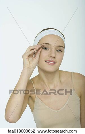 Stock Image - Teenage girl tweezing eyebrows. Fotosearch