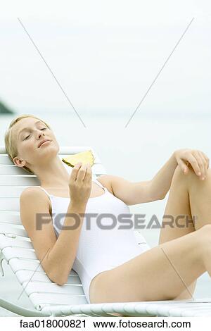 Teenage girl wearing bathing suit, sitting in lounge chair, holding slice of pineapple View Large Photo Image Stock Image - Teenage girl wearing bathing suit, sitting in lounge chair, holding slice of pineapple. Fotosearch