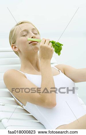 Teenage girl wearing bathing suit, sitting in lounge chair, smelling celery stalk View Large Photo Image Stock Image - Teenage girl wearing bathing suit, sitting in lounge chair, smelling celery stalk. Fotosearch