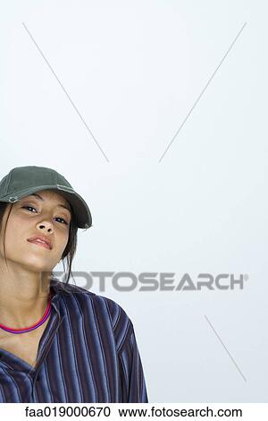 Teenage girl wearing large button down shirt and baseball cap, portrait View Large Photo Image Stock Image - Teenage girl wearing large button down shirt and baseball cap, portrait. Fotosearch