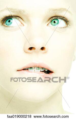Stock Photo - Teenage girl with braces biting lip, extreme close-up. Fotosearch