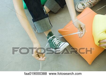 Teenager tying laces of canvas shoe, partial high angle view View Large Photo Image Stock Photo - Teenager tying laces of canvas shoe, partial high angle view. Fotosearch