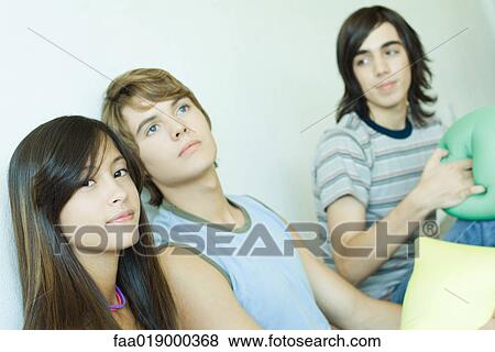 Three teen friends holding cushions View Large Photo Image Stock Photo - Three teen friends holding cushions. Fotosearch