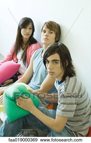 Stock Photo - Three teen friends sitting on floor, holding cushions. Fotosearch