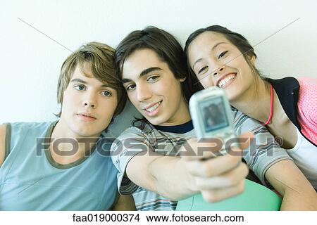 Three teen friends taking self portrait with cell phone View Large Photo Image Picture - Three teen friends taking self portrait with cell phone. Fotosearch