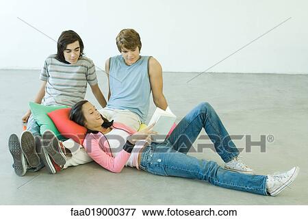 Three teen friends, teen girl reclining on teen boys knees, reading View Large Photo Image Stock Photo - Three teen friends, teen girl reclining on teen boys knees, reading. Fotosearch