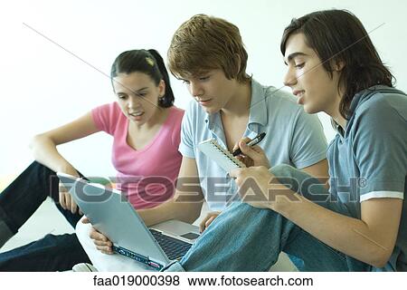 Three teen friends using laptop together, one taking notes View Large Photo Image Stock Photo - Three teen friends using laptop together, one taking notes. Fotosearch