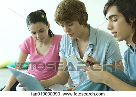 Three teen friends using laptop together, one taking notes View Large Photo Image Stock Photo - Three teen friends using laptop together, one taking notes. Fotosearch