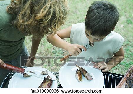 Two boys eating grilled meat View Large Photo Image Stock Photograph - Two boys eating grilled meat. Fotosearch