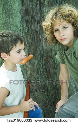 Two boys, one eating hot dog from fork View Large Photo Image Stock Image - Two boys, one eating hot dog from fork. Fotosearch