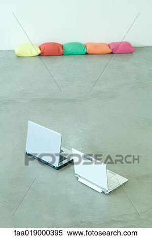 Two laptops on floor, cushions in background View Large Photo Image Stock Photography - Two laptops on floor, cushions in background. Fotosearch