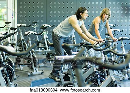Two men riding exercise bikes View Large Photo Image Picture - Two men riding exercise bikes. Fotosearch