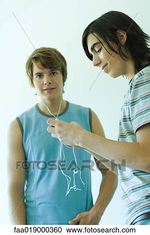 Stock Image - Two teen boys listening to MP3 player. Fotosearch