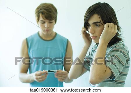 Stock Image - Two teen boys listening to MP3 player. Fotosearch