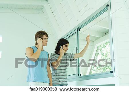 Two teenage boys using cell phones, looking out window View Large Photo Image Stock Photo - Two teenage boys using cell phones, looking out window. Fotosearch