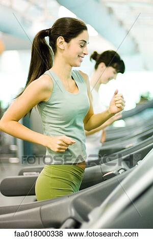 Stock Photo - Two women running on treadmills. Fotosearch