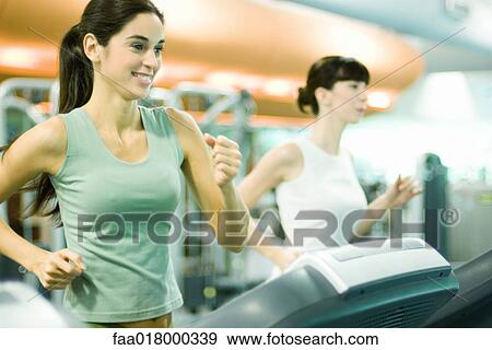 Stock Photo - Two women running on treadmills. Fotosearch