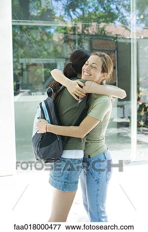 Stock Photo - Two young women hugging each other, side view. Fotosearch