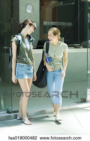 Stock Image - Two young women leaving health club together, one making excited expression. Fotosearch