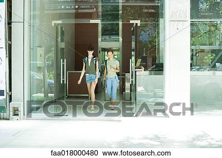 Two young women walking toward doorway together, front view View Large Photo Image Stock Image - Two young women walking toward doorway together, front view. Fotosearch