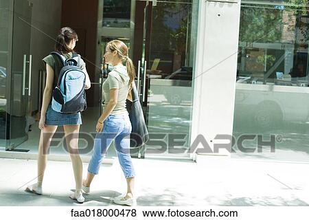 Stock Photo - Two young women walking toward doorway together. Fotosearch