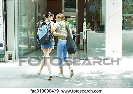 Two young women walking toward doorway together, arms around each other View Large Photo Image Stock Photo - Two young women walking toward doorway together, arms around each other. Fotosearch