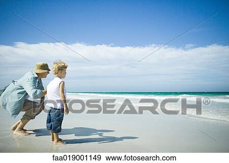 Woman and boy standing on beach, looking towards waves View Large Photo Image Stock Photo - Woman and boy standing on beach, looking towards waves. Fotosearch