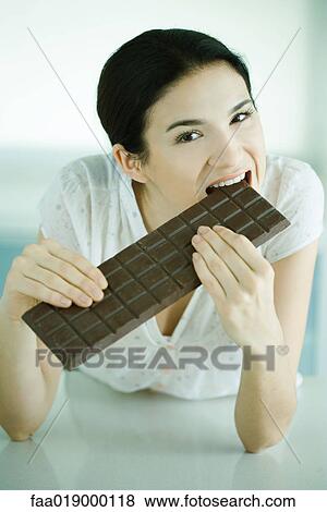 Woman biting into large bar of chocolate View Large Photo Image Stock Photo - Woman biting into large bar of chocolate. Fotosearch