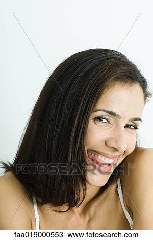 Woman biting tongue, smiling at camera, portrait View Large Photo Image Stock Image - Woman biting tongue, smiling at camera, portrait. Fotosearch