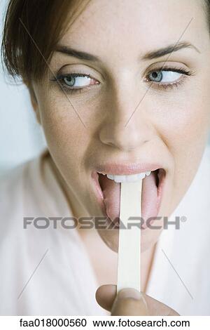 Stock Image - Woman having tongue held down with tongue depressor. Fotosearch