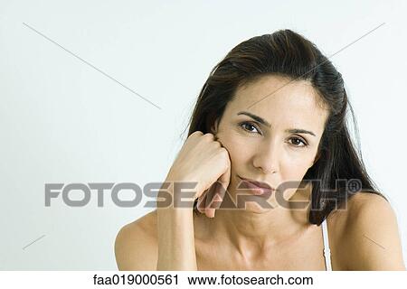 Stock Image - Woman holding head, pouting, portrait. Fotosearch