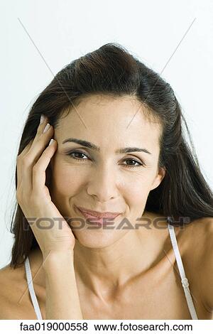 Stock Photo - Woman holding head, smiling at camera, portrait. Fotosearch