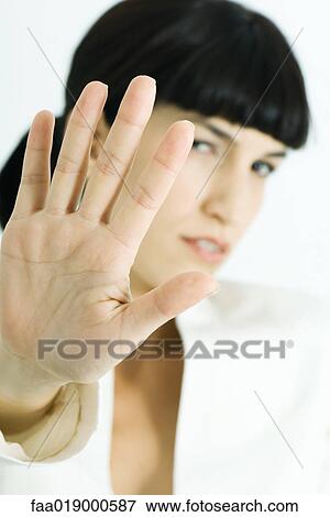 Stock Photo - Woman holding up palm to camera, portrait. Fotosearch
