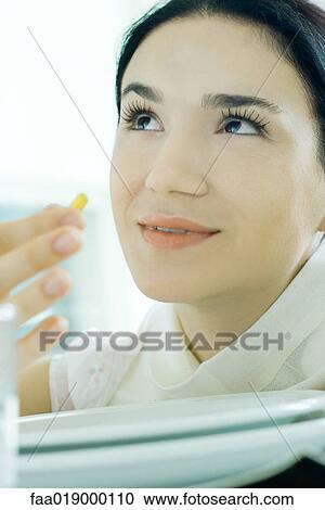 Woman holding up vitamin, looking up View Large Photo Image Stock Image - Woman holding up vitamin, looking up. Fotosearch