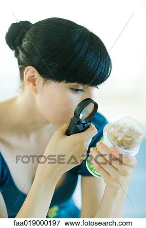Stock Photo - Woman looking at yogurt through magnifying glass. Fotosearch