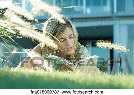 Woman lying in grass, reading book View Large Photo Image Stock Photo - Woman lying in grass, reading book. Fotosearch
