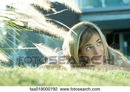 Woman lying in grass, with book, looking up View Large Photo Image Stock Image - Woman lying in grass, with book, looking up. Fotosearch
