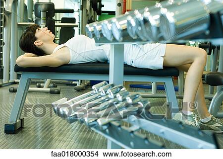 Woman lying on weight bench, doing sit-ups View Large Photo Image Picture - Woman lying on weight bench, doing sit-ups. Fotosearch
