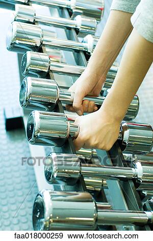 Stock Photo - Woman picking up dumbbells. Fotosearch