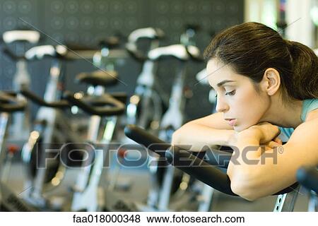 Woman riding exercise bike, slouching on handlebars View Large Photo Image Stock Photo - Woman riding exercise bike, slouching on handlebars. Fotosearch