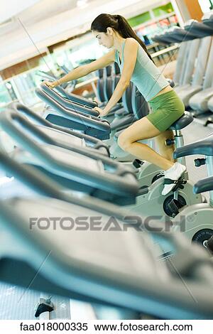Stock Photography - Woman riding exercise bike. Fotosearch