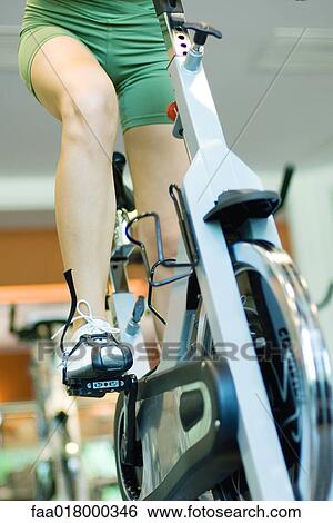 Stock Photograph - Woman riding exercise bike, waist down. Fotosearch