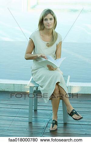 Woman sitting and holding book, water in background View Large Photo Image Stock Image - Woman sitting and holding book, water in background. Fotosearch