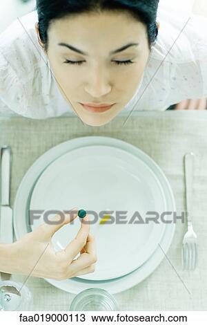 Woman sitting at empty plate holding vitamin View Large Photo Image Stock Image - Woman sitting at empty plate holding vitamin. Fotosearch
