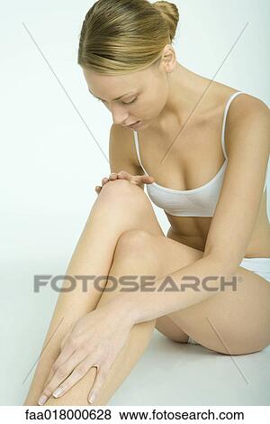 Woman sitting in underclothes, touching legs View Large Photo Image Stock Photo - Woman sitting in underclothes, touching legs. Fotosearch
