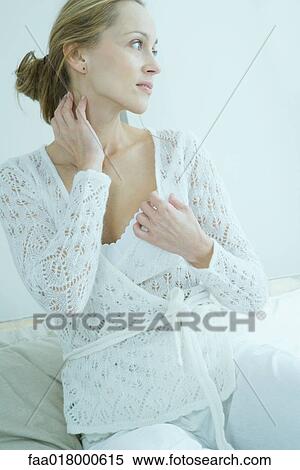 Woman sitting on bed, hand on neck, looking away View Large Photo Image Stock Photography - Woman sitting on bed, hand on neck, looking away. Fotosearch