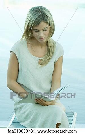 Woman sitting, reading book, water in background View Large Photo Image Stock Image - Woman sitting, reading book, water in background. Fotosearch