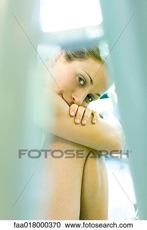 Woman sitting with head on knees, smiling at camera, focus on background View Large Photo Image Stock Image - Woman sitting with head on knees, smiling at camera, focus on background. Fotosearch