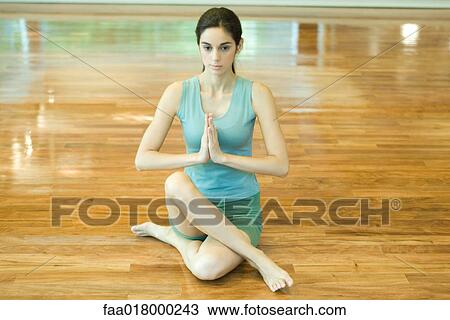 Stock Image - Woman sitting with legs crossed and hands in prayer position . Fotosearch