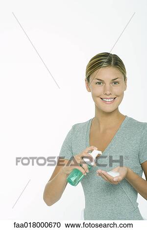 Stock Image - Woman squeezing beauty product into palm of hand. Fotosearch